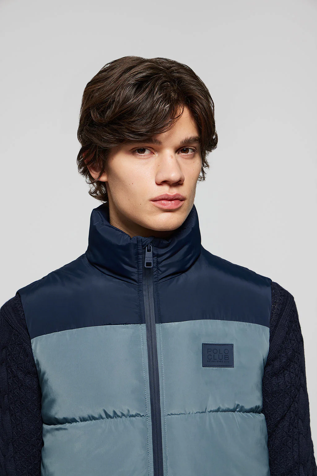 Denim-blue puffer vest with high collar and logo patch
